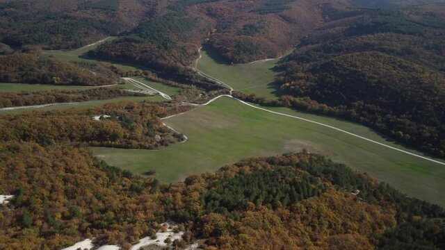 Flying over the valley in the Mangup gorge. Colorful trees and a green meadow. Bright colors of the Crimean autumn. 4k drone video