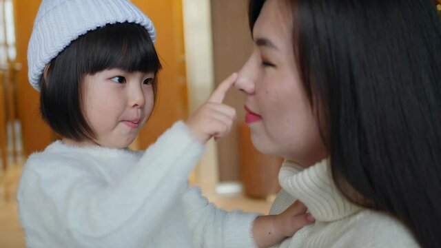 Korean family mom and daughter child in white sweater and knitted hat sitting