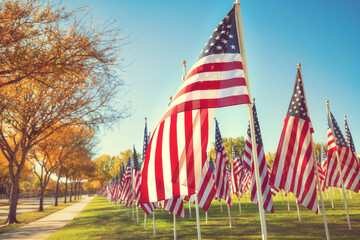 American flags standing in the green field on a beautiful autumn day. Veterans Day display. Blue sky and autumn trees background.   - 469378052