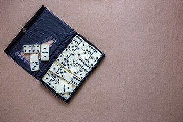 White dominoes in black plastic case on brown background, top view. Domino game 