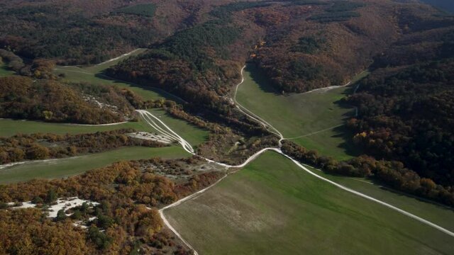 Flying over the valley in the Mangup gorge. Colorful trees and a green meadow. Bright colors of the Crimean autumn. 4k drone video
