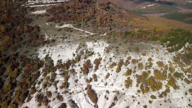 Flying over a white rock with bright trees and shrubs in the Mangup gorge, Crimea. Autumn colors background