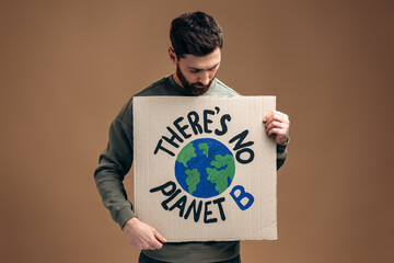 There is no planet B. Caucasian serious man holding carton placard with signs and looking at it....