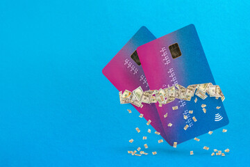 Passive income. Cash flow concept. Passive earnings. A credit card hangs in the air on an blue background surrounded by dollars from which small bills are falling
