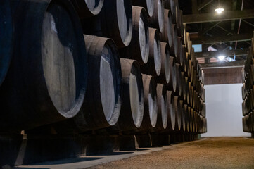 Old porto lodge with rows of oak wooden casks for slow aging of fortified ruby or tawny porto wine in Vila Nova de Gaia, Portugal