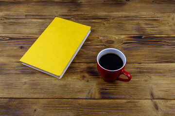 Cup of coffee and book on wooden table