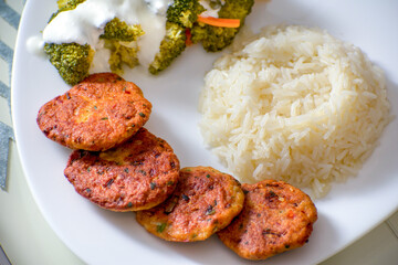 Chicken meatballs with rice and broccoli salad on a white plate