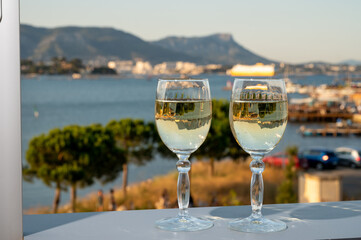 Summer on French Riviera, drinking cold white wine from Cotes de Provence on outdoor terrase with view on harbour of Toulon, Var, France