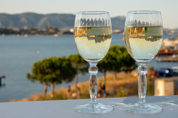 Summer on French Riviera, drinking cold white wine from Cotes de Provence on outdoor terrase with view on harbour of Toulon, Var, France