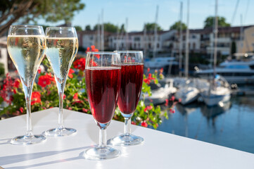 Summer party with kir royal cocktail, tasting of French brut champagne sparkling wine and cold creme cassis in glasses in yacht harbour of Port Grimaud near Saint-Tropez, French Riviera vacation