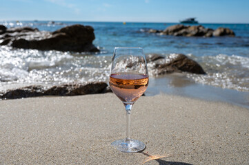 Summer time in Provence, glass of cold rose wine on sandy beach and blue sea near Saint-Tropez, Var department, France