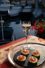 Drinking of white cold champagne, bliny with red caviar and view on Port Grimaud near Saint-Tropez in summer