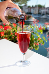 Summer party with kir royal cocktail, pouring of French brut champagne sparkling wine and cold cassis in glasses in yacht harbour of Port Grimaud near Saint-Tropez, French Riviera vacation, France