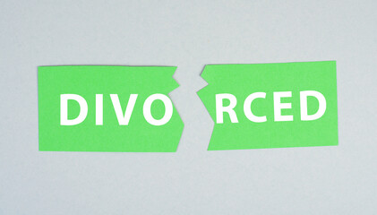 Torn apart green paper with the word divorced on a grey background, end of marriage, separation, relationship