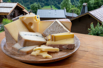 Cheese collection, wooden board with French cheeses comte, beaufort, abondance, emmental, morbier...