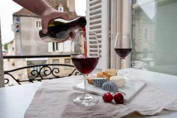 Tasting of burgundy red wine from grand cru pinot noir  vineyards with french goat cheeses and view on old town street in Burgundy wine region, France