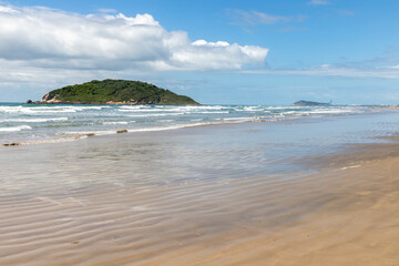 Beach view with sand, waves and island in background
