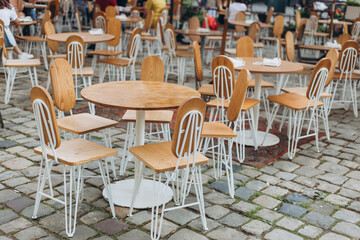 Fototapeta na wymiar Empty chairs in outdoor cafe or restaurant on summer day. Reastaurant tables waiting for customers, old town