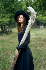 woman in black witch costume in forest nature posing