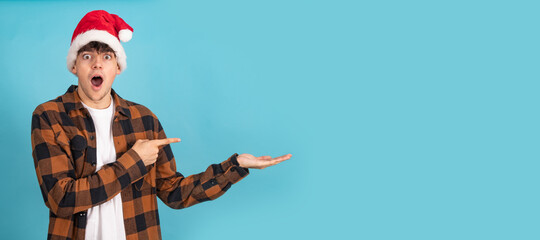 isolated boy with santa claus hat and surprised expression isolated on background pointing