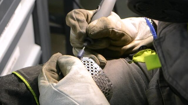 Man in work uniform grinds metal detail by hand close-up. Grinding metal detail