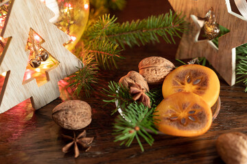 Christmas still life with slices of fresh persimmon, fir-tree, walnuts and a star of cardamom