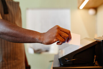 Horizontal side view shot of unrecognizable cafe worker adding information about order using modern cash register machine with touchscreen