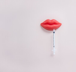 Medical syringe and plasticine red lips. Lip injection creative concept. Selective focus, square orientation, copy space