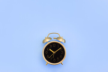 Vintage gold alarm clock on a blue background. Minimal time concept. Copy space