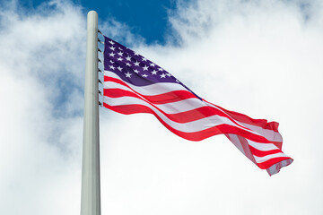 Fototapeta premium Large U.S. Flag blowing in a strong wind on a cloudy sky