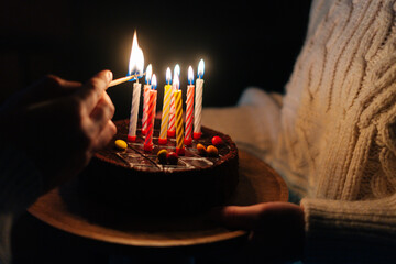 Close-up of unrecognizable man burning candles, woman holding in hands birthday cake with six...