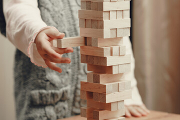 The hands of a child playing a board game, builds a tower from wooden blocks