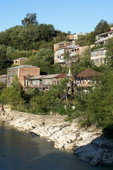 Fototapeta premium A picturesque village nestled along a serene river, surrounded by lush greenery and scenic landscapes. The tranquil atmosphere captures the beauty of nature and rural life.