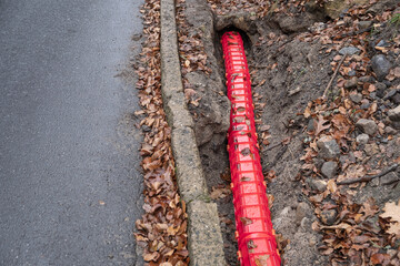 Network Buildout high-speed Internet Network cables in red Cable Protector Wire Cover are buried underground on