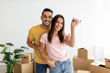 Happy multiracial couple showing house key, moving to new apartment together
