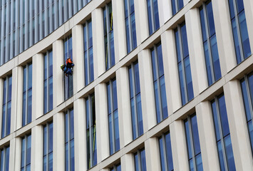 Window washer. Low Angle View of Worker Cleaning Modern Office Building. Manchester, UK.