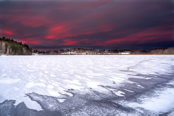 winter landscape with snow-covered trees and an icy lake. red sky
