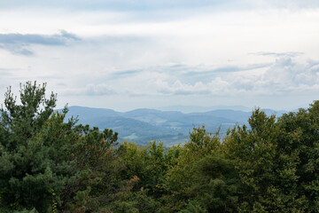 Hazy view of the Blue Ridge Mountains of North Carolina seen beyond a dark green tree line, overcast sky copy space, horizontal aspect