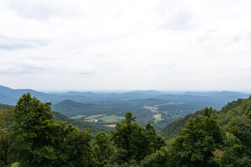 Scenic overlook of the Blue Ridge Mountains on a hazy, overcast day, deep green tree line in the foreground, horizontal aspect