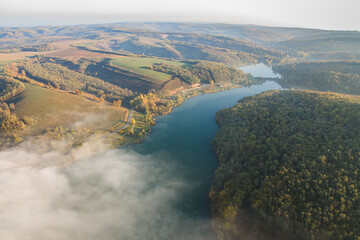 Aerial view of an autumn scene with foggy landscape and a lake