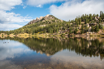Reflection of a wooded hill in a lake of Rocky Mountain National Park