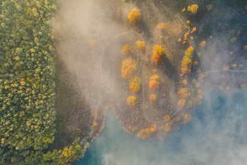 Aerial view of an autumn scene with foggy landscape and a lake