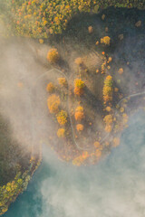 Aerial view of an autumn scene with foggy landscape and a lake