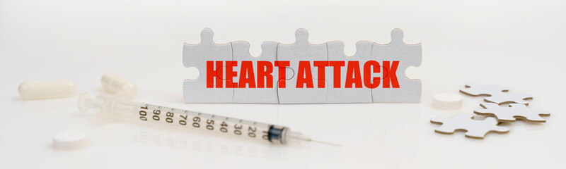 On a white background lie a syringe, pills and puzzles with the inscription - HEART ATTACK