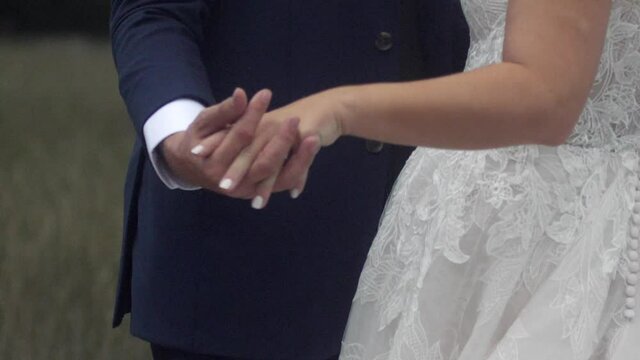 Bride and groom holding hands and being repositioned by photographer