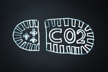 CO2 carbon dioxide footprint symbol or concept. Painted footprint on black memo board with text CO2