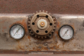 Gritty, rusty cog-wheel gear and pressure gauges on a beat up classic car in need of restoration 