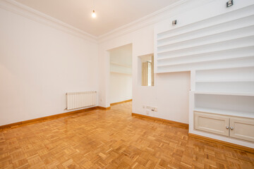 Living room in a period building with parquet floors, plaster shelves and white painted walls in a...