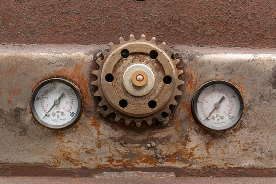 Gritty, rusty cog-wheel gear and pressure gauges on a beat up classic car in need of restoration 