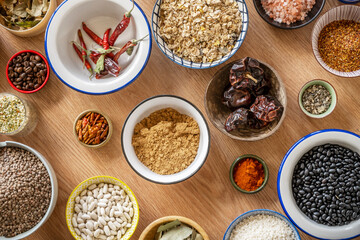 set of bowls with ingredients for fusion food recipes. Black beans, star anise, rice, chia and cocoa, star anise, black pepper, panela